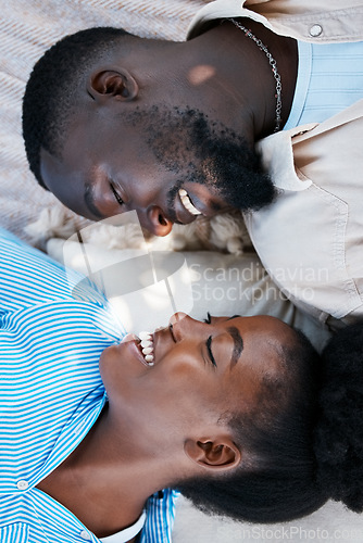 Image of Love, happiness and black couple laying outdoors on the floor with blankets to relax in a park. Happy, care and African man and woman with a smile resting while on a date in nature by a garden.