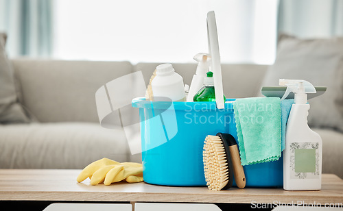 Image of House, cleaning service and container with spray bottle, rubber gloves and scrub in home living room or apartment interior. Spring clean day, career or housekeeping with household products on table