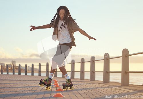 Image of Roller skates, beach and sport with a man riding around training cone for fun, fitness and exercise at the seaside promenade. Hipster male athlete skating outside for leisure, health and recreation