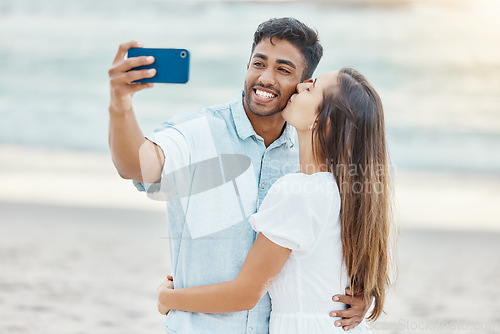 Image of Travel, vacation and selfie by couple kiss on a beach holiday, bonding and having fun on seaside getaway. Young man and woman embrace, enjoying their relationship and romance on a romantic trip