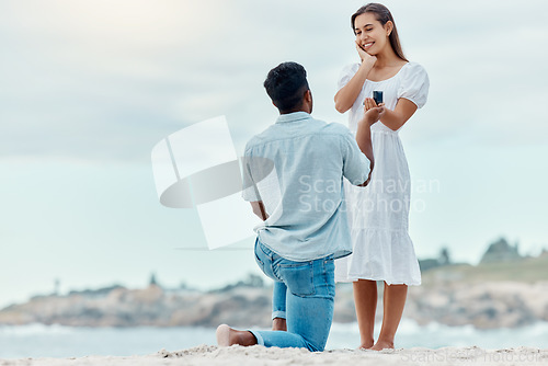 Image of Beach proposal, engagement and surprise woman for love, care and relationship commitment together. Young, engaged and happy marry me couple, summer seaside date and special romance marriage outdoors