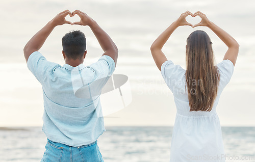 Image of Couple hands, back heart love sign and passion, affection or romantic emoji by the ocean. Romance, man and woman, hand symbol or emotion shape. Intimacy or adoration, support or devotion gesture.