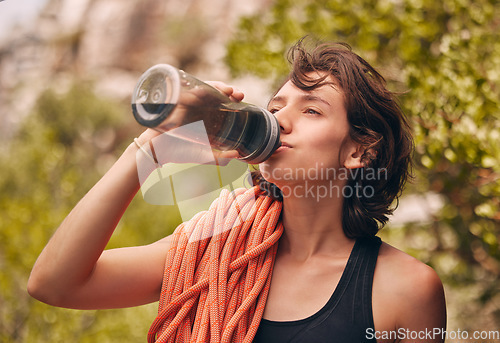 Image of Water bottle, hiking and exercise with woman feeling thirsty and staying hydrated during fitness workout or rock climbing in nature. Health, wellness and electrolyte with athlete female on adventure