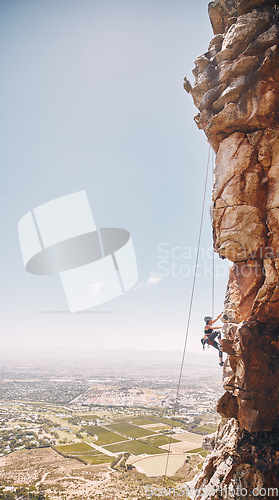 Image of Person rock climbing on a mountain cliff for a challenge in nature with a blue sky and copy space. Woman climber on a rock wall for a fitness workout, exercise and sports training outdoors.