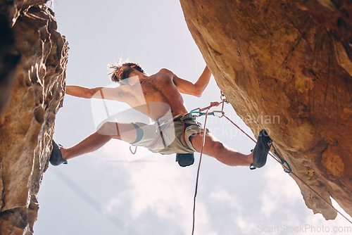 Image of Fitness, rock climbing and strong mountain climber on a cliff with ropes in summer challenge and extreme exercise. Danger, courage and healthy man fearless, sports and big rocks or stone below view