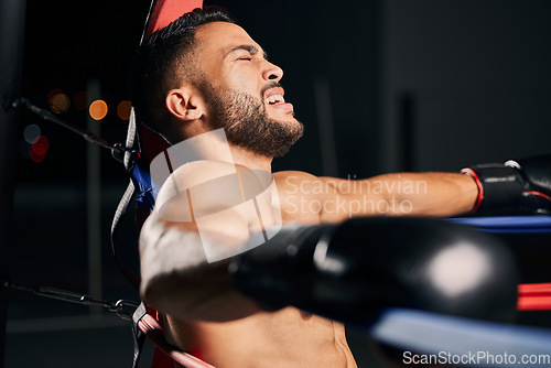 Image of Boxing, pain and tired boxer in the ring fighting in a sports arena or stadium for a competitive championship. Fitness, exercise and intense training workout by a young Latino fighter with an injury