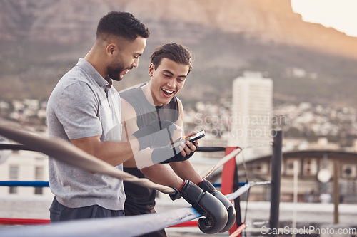 Image of Boxer and coach with phone after training, exercise or workout reading social media meme online. Sport athlete smile and laugh after coaching mma, muay thai and boxing outdoor in a fighting ring