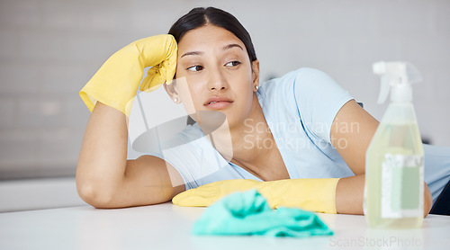 Image of Thinking, cleaner and woman at table in home tired of spring cleaning the kitchen interior. Housekeeper girl with domestic gloves and detergent unhappy, frustrated and moody with tidy job.