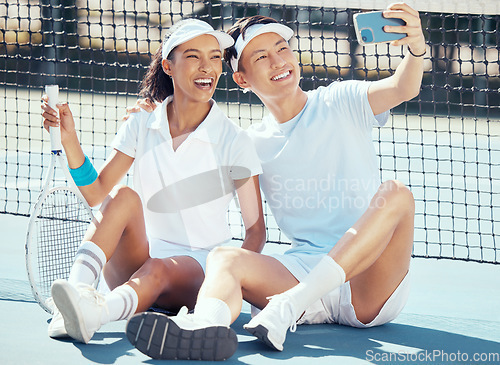 Image of Selfie, sports or couple sitting on a tennis court resting after exercise, practice or training. Wellness, fitness or health with an interracial man and woman with sport racket taking a phone picture