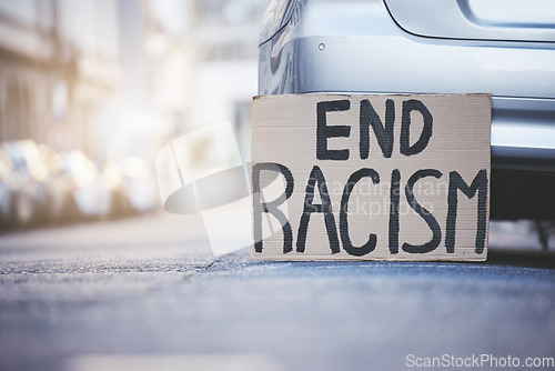 Image of End racism sign cardboard poster in urban street background for solidarity, human rights and race problem. Advertising of protest board for freedom, equality and stop violence with mockup lens flare