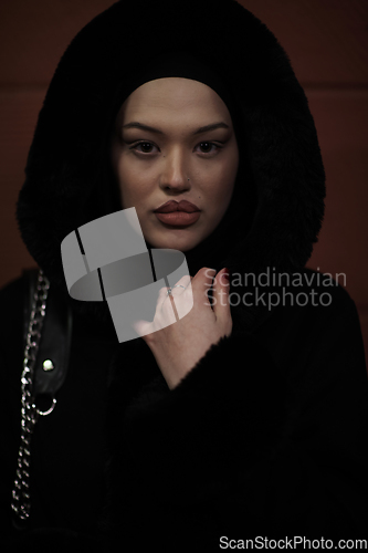 Image of Muslim woman walking on urban city street on a cold winter night wearing hijab