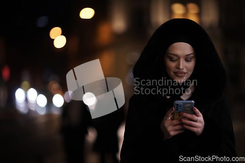 Image of Muslim woman walking on urban city street on a cold winter night