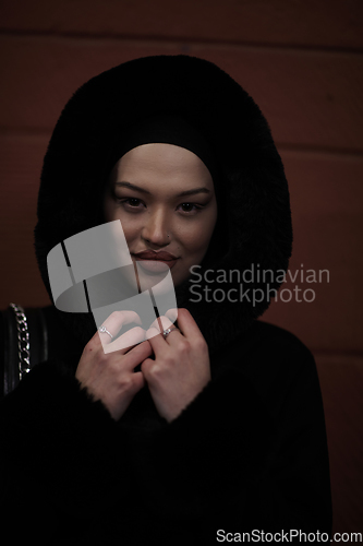 Image of Muslim woman walking on urban city street on a cold winter night wearing hijab