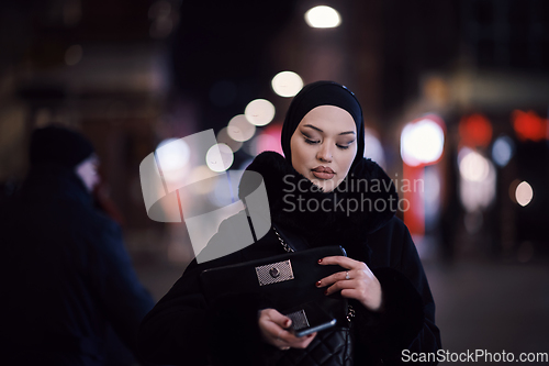 Image of Muslim woman walking on urban city street on a cold winter night wearing hijab