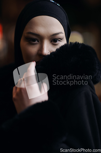 Image of Muslim woman walking on urban city street on a cold winter night wearing hijab