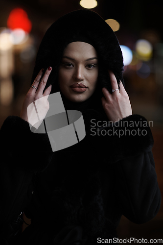 Image of Muslim woman walking on an urban city street on a cold winter night wearing hijab