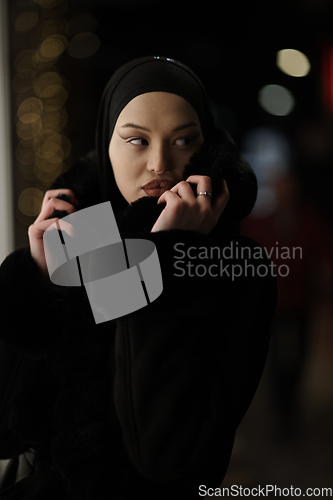 Image of Muslim woman walking on urban city street on a cold winter night wearing hijab