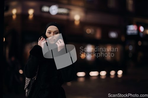 Image of Muslim woman walking on urban city street on a cold winter night wearing hijab