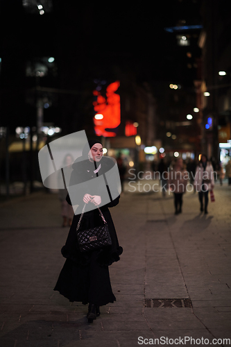 Image of Muslim woman walking on urban city street on a cold winter night wearing hijab