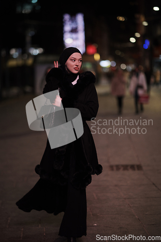 Image of Muslim woman walking on urban city street on a cold winter night wearing hijab