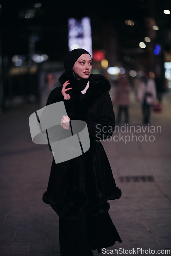 Image of Muslim woman walking on urban city street on a cold winter night wearing hijab