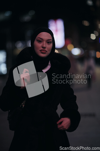 Image of Muslim woman walking on urban city street on a cold winter night wearing hijab