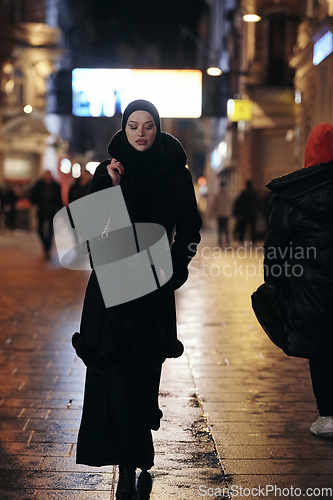 Image of Muslim woman walking on urban city street on a cold winter night wearing hijab