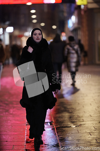 Image of Muslim woman walking on urban city street on a cold winter night wearing hijab