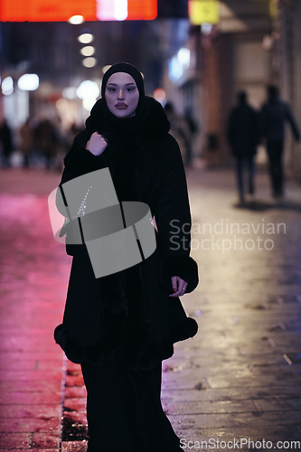 Image of Muslim woman walking on urban city street on a cold winter night wearing hijab