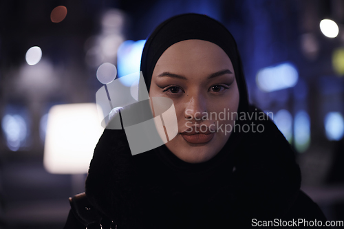 Image of Muslim woman walking on urban city street on a cold winter night wearing hijab