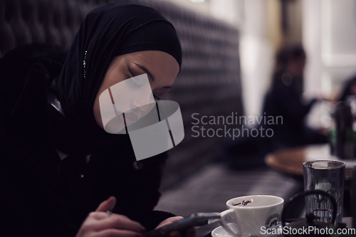 Image of Muslim woman walking on an urban city street on a cold winter night wearing hijab