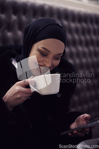 Image of happy Middle Eastern female having break take a cup of tea in restaurant