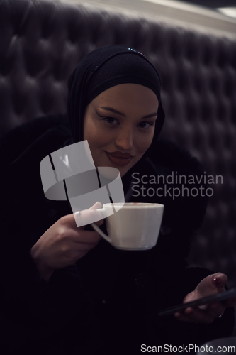 Image of happy Middle Eastern female having break take a cup of tea in restaurant