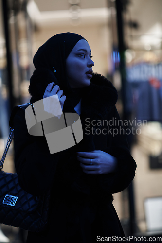 Image of Muslim woman walking on an urban city street on a cold winter night wearing hijab