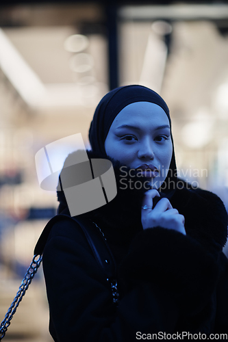 Image of Muslim woman walking on an urban city street on a cold winter night wearing hijab