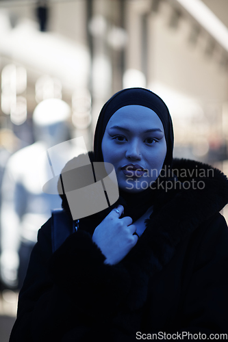 Image of Muslim woman walking on an urban city street on a cold winter night wearing hijab