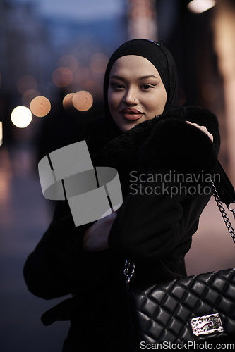 Image of Muslim woman walking on an urban city street on a cold winter night wearing hijab