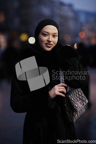 Image of Muslim woman walking on an urban city street on a cold winter night wearing hijab