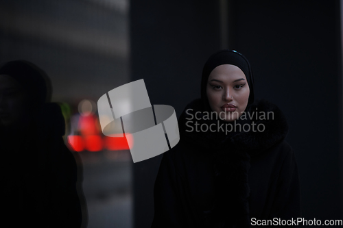 Image of Muslim woman walking on an urban city street on a cold winter night wearing hijab