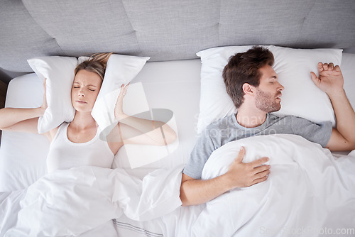 Image of Sleeping, snoring and wife with pillow on ears to stop noise from husband in bed with sleep problem. Insomnia, frustration and stress with tired woman in bedroom lying next to man with apnea