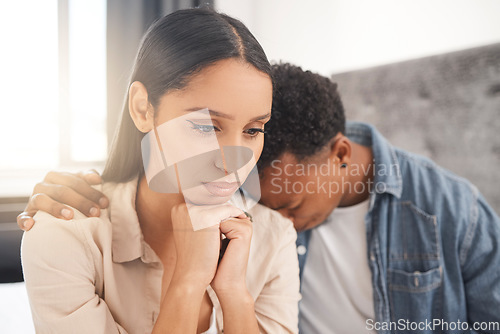 Image of Upset couple fighting, arguing or breaking up while sitting on their bed in the bedroom at home. Sad man crying on the shoulder of his thinking wife while talking about divorce or difficult problems.