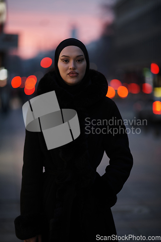 Image of Muslim woman walking on an urban city street on a cold winter night wearing hijab