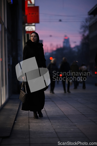 Image of Muslim woman walking on an urban city street on a cold winter night wearing hijab