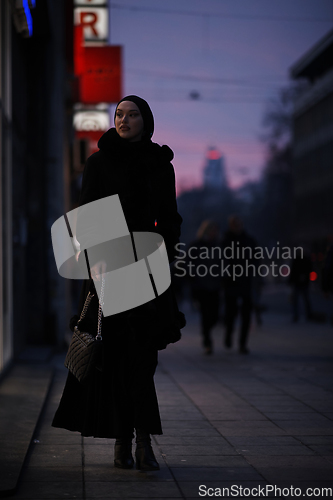 Image of Muslim woman walking on an urban city street on a cold winter night wearing hijab