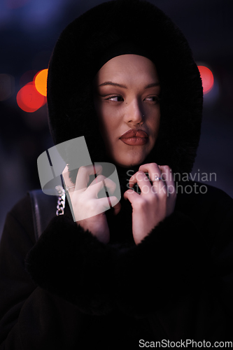 Image of Muslim woman walking on an urban city street on a cold winter night wearing hijab