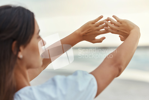 Image of Woman at the beach in the morning for wellness, mental health with the ocean, sunrise and stretching arms. Young, calm and relax person with natural view of the horizon in nature and sea water