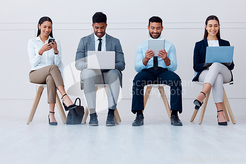 Image of Business people, waiting room and tech with some on mobile, laptop or tablet. Happy workers, group or candidates on technology, computer or phone waiting for a job interview, hiring or recruitment.