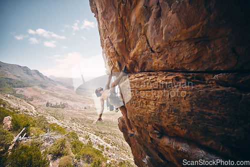 Image of Rock climbing, rope and fearless mountain climber on a cliff, big rocks and risky challenge alone in summer. Mountaineering, bouldering and strong man training his body for balance outdoors in nature