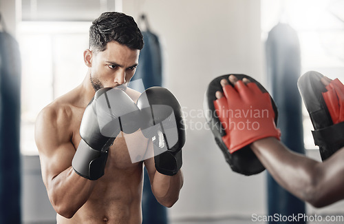 Image of Boxing gym, fighting pad and man training with athlete coach for a fitness cardio exercise session. Strength, focus and fighter workout for punch technique with professional sports equipment.