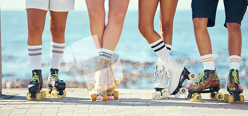 Image of Roller skates, friends and beach with a group of people on the promenade at the beach with the sea in the background. Summer, fun and lifestyle with a skaters skating outside during a sunny day